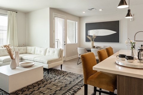 a living room and dining room area with a white couch and a table and chairs